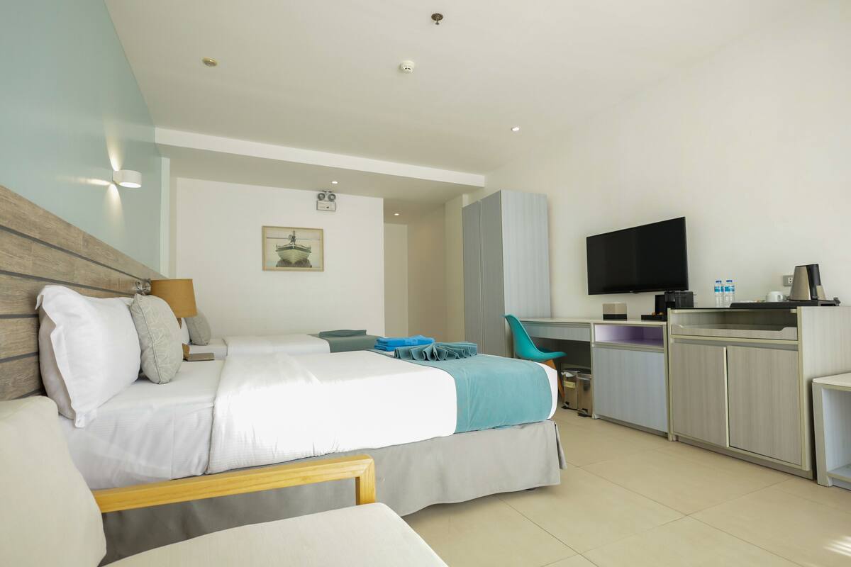 A hotel room with a bed, a desk, a television, and a kitchenette.