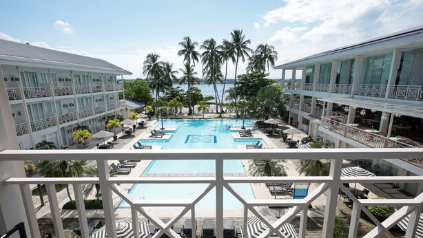 A hotel with a large pool, multiple balconies, and palm trees. - Club Samal Resorts Development Inc (Samal)