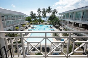Un hotel con una piscina grande, varios balcones y palmeras.
