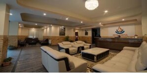 A spacious lobby with multiple seating areas, a reception desk, and a chandelier. - Hotel Lhayul (Ha)