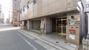 A building with a closed entrance, a signboard, and a vending machine on the sidewalk. - The Aquarius Inn - Hostel (Fukuoka)