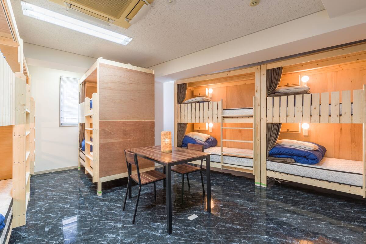 A room with bunk beds, a wooden desk, and a table with chairs.