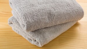 A folded gray towel on a wooden surface. - The Aquarius Inn - Hostel (Fukuoka)