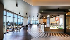 A spacious hotel lobby with large windows, a check-in counter, and a seating area. - Mercure Ambassador Ulsan (Ulsan)