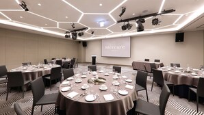 A conference room with hexagonal ceiling lights, multiple tables set for dining, and a projection screen displaying "Mercure Hotels". - Mercure Ambassador Ulsan (Ulsan)