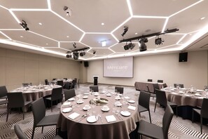 A conference room with hexagonal ceiling lights, multiple tables set for dining, and a projection screen displaying "Mercure Hotels". - Mercure Ambassador Ulsan (Ulsan)