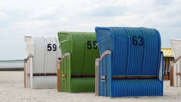 Beach chairs with numbers 59, 55, and 63 on a sandy beach.