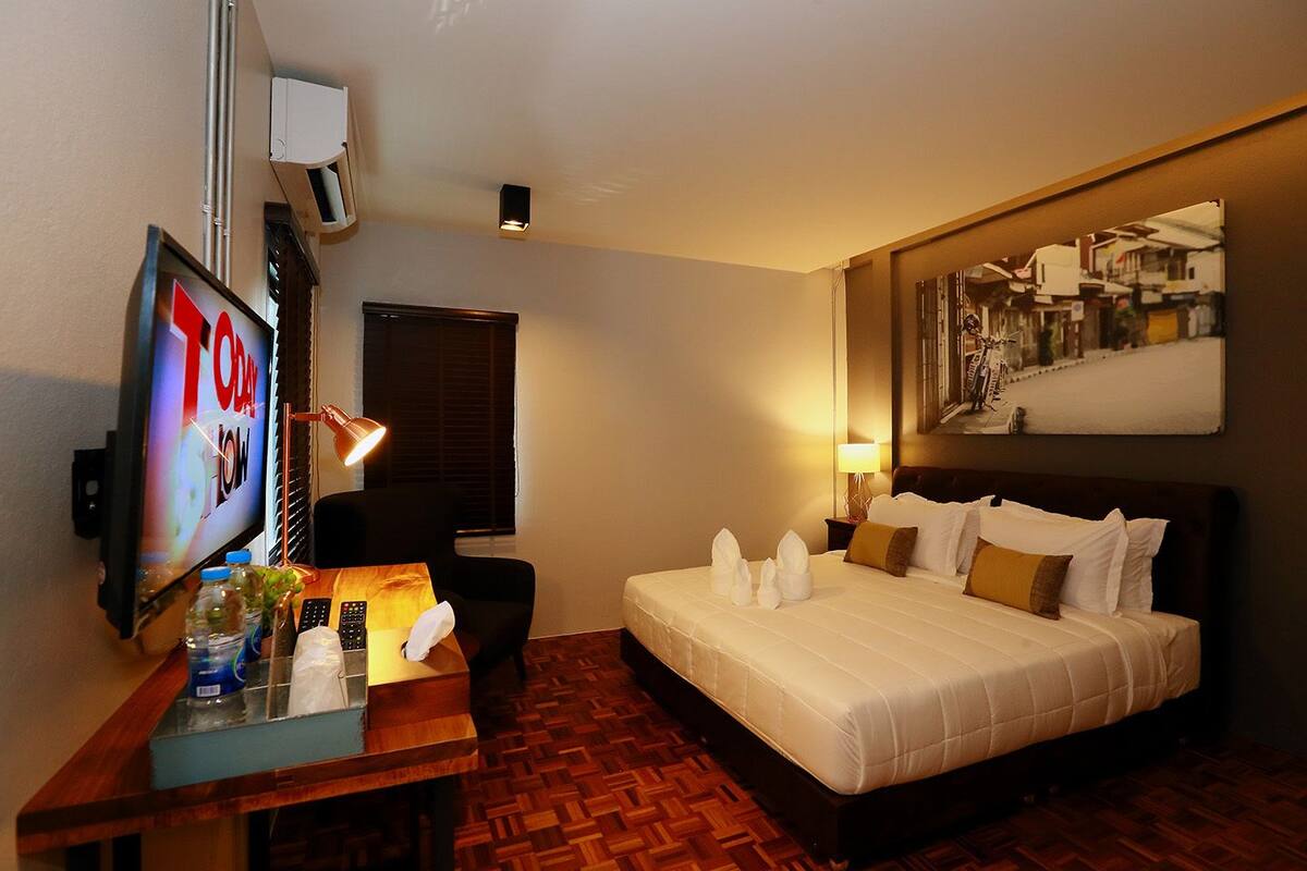 Une chambre d’hôtel avec un lit, un bureau avec une télévision, une lampe et un tableau au mur.