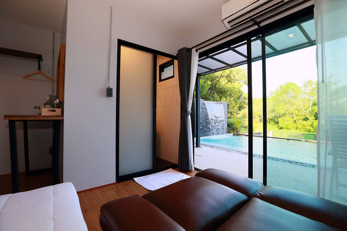 Une chambre d’hôtel moderne dotée d’une grande porte-fenêtre coulissante donnant accès à un espace piscine extérieur.