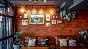 Un coin salon accueillant avec des canapés en cuir, un mur en bois orné de tableaux et une plante suspendue.