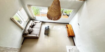 Una habitación con techos altos, un sofá, una mesita de madera y una lámpara colgante.