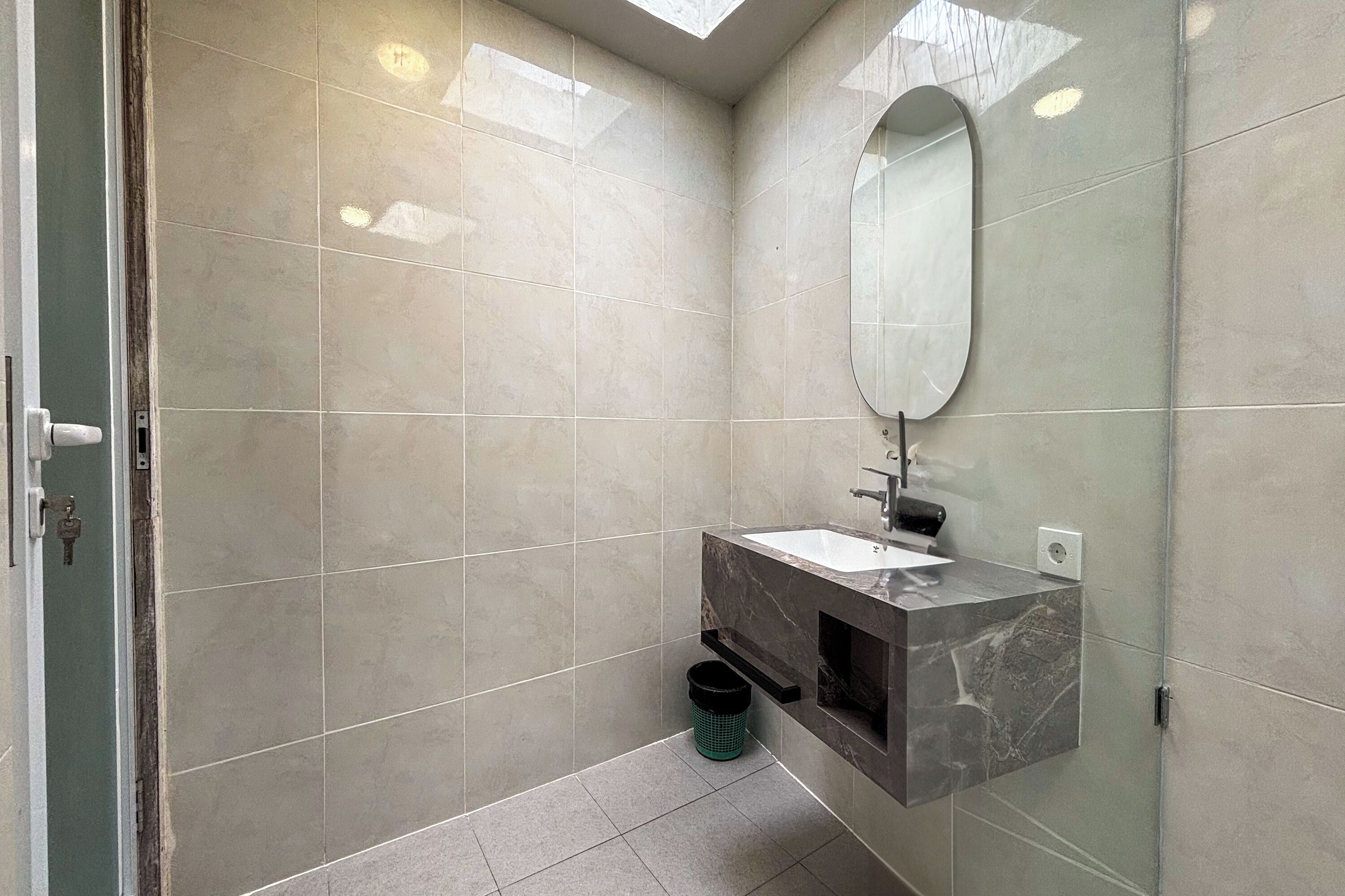 A modern bathroom with a glass shower enclosure, a marble sink, and a large mirror.
