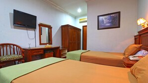 A hotel room with two beds, a desk, a chair, a television, a wardrobe, and a painting on the wall. - Hotel Sumatera (Medan)