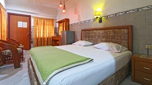 A hotel room with a bed, a desk, a chair, a television, and a nightstand. - Hotel Melati (Medan)