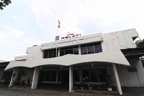 A modern hotel with a flat roof, large windows, and a flag on top. - Hotel Melati (Medan)