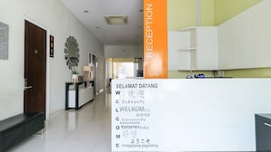 A reception area with a sign displaying multilingual welcome messages. - Home Guesthouse by Zuzu (Surabaya)