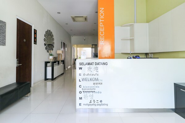 A reception area with a sign displaying multilingual welcome messages. - Home Guesthouse by Zuzu (Surabaya)