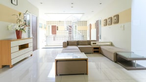 A modern living room with a sofa, a glass coffee table, a wooden cabinet, and a potted plant. - Home Guesthouse by Zuzu (Surabaya)