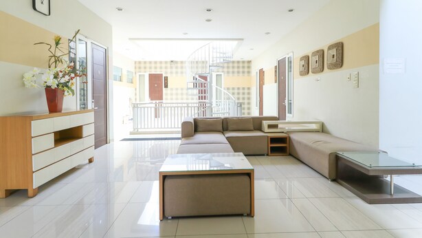 A modern living room with a sofa, a glass coffee table, a wooden cabinet, and a potted plant. - Home Guesthouse by Zuzu (Surabaya)