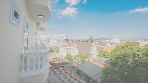 Un edificio residencial con balcón, techo rojo y vistas a otros edificios en la distancia.