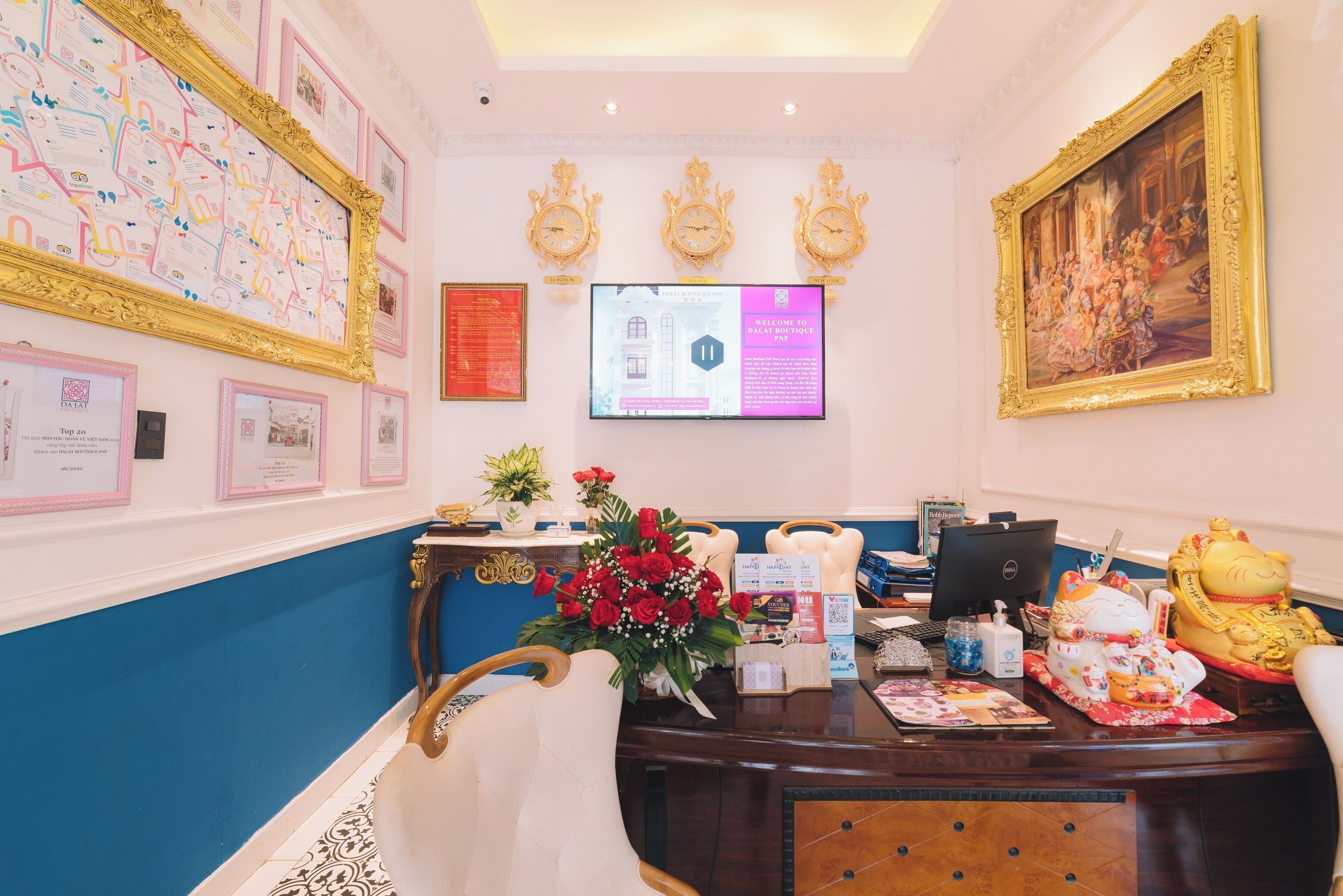 A reception area with a desk, computer, framed certificates, and a large painting.