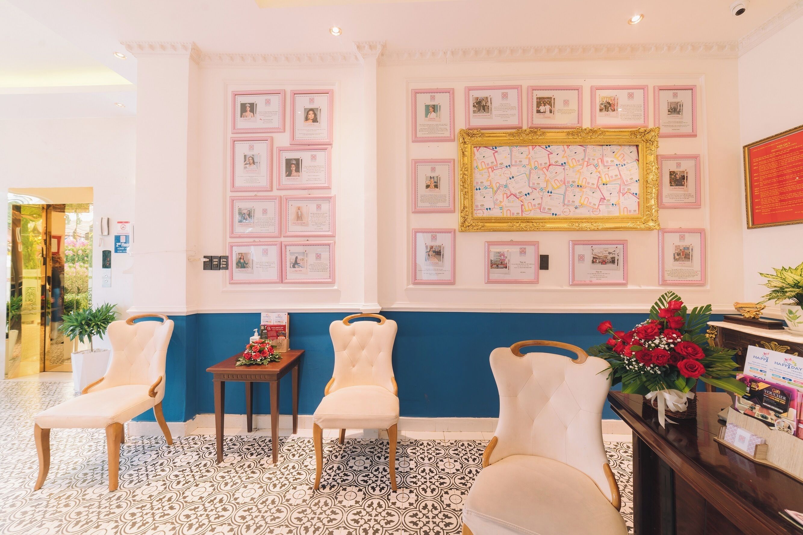 A reception area with framed certificates on the wall, a reception desk with a vase of flowers, and three upholstered chairs.