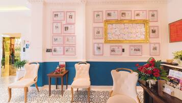 A reception area with framed certificates on the wall, a reception desk with a vase of flowers, and three upholstered chairs.