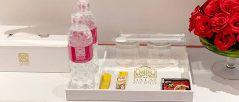 A tray with a water bottle, a tissue box, a small yellow item, a red item, and a card on a white surface.