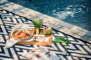 A poolside setup with a tray of food, a drink, and a plant. - Scene Bangkok Noi (Bangkok)