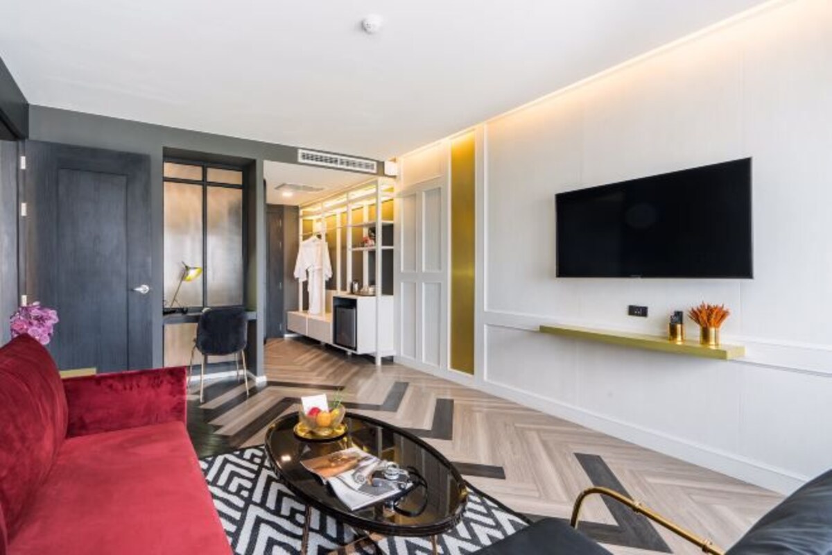 A modern living room with a red sofa, a black coffee table, and a TV mounted on the wall.
