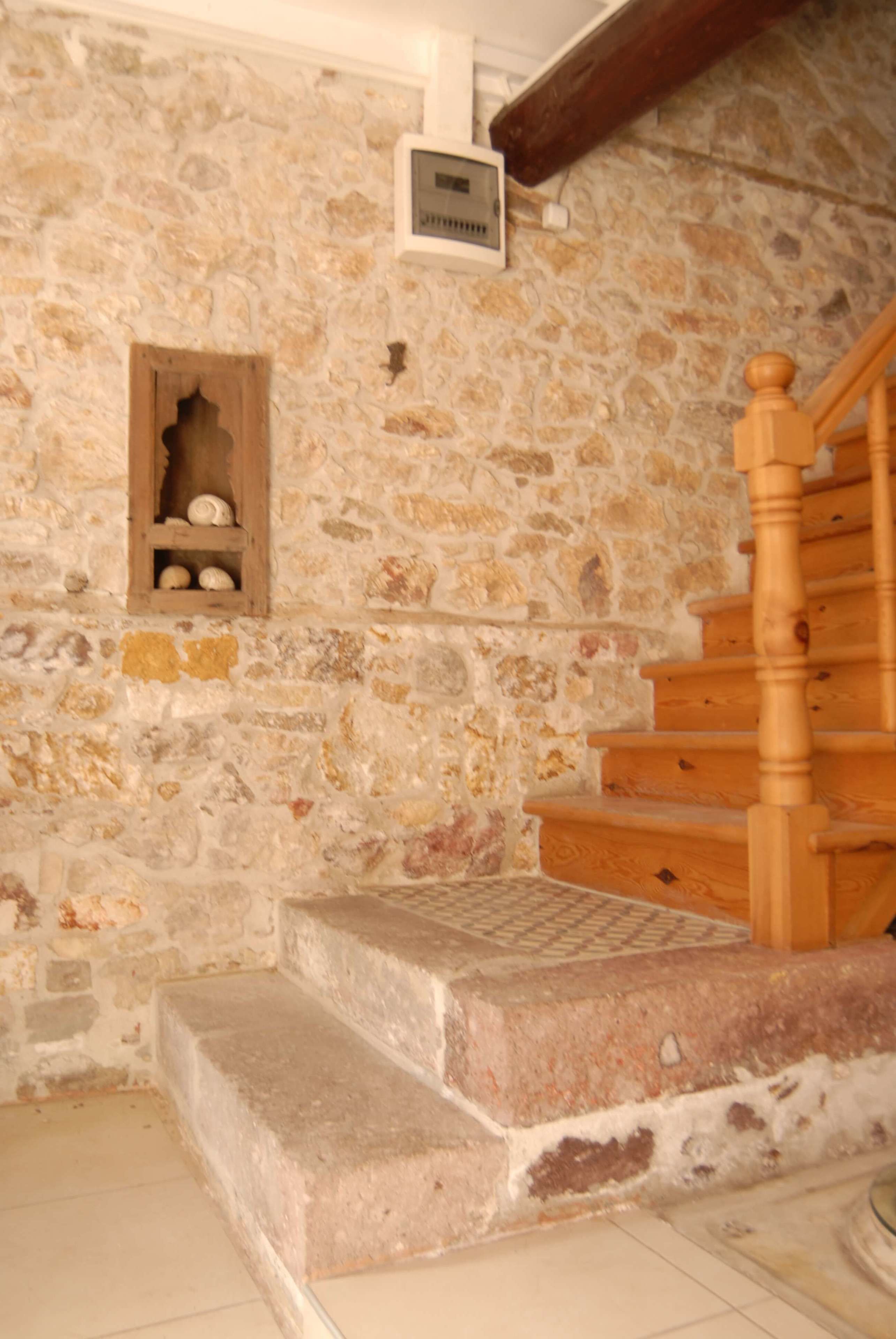Un muro de piedra con un estante de madera y una escalera de madera.