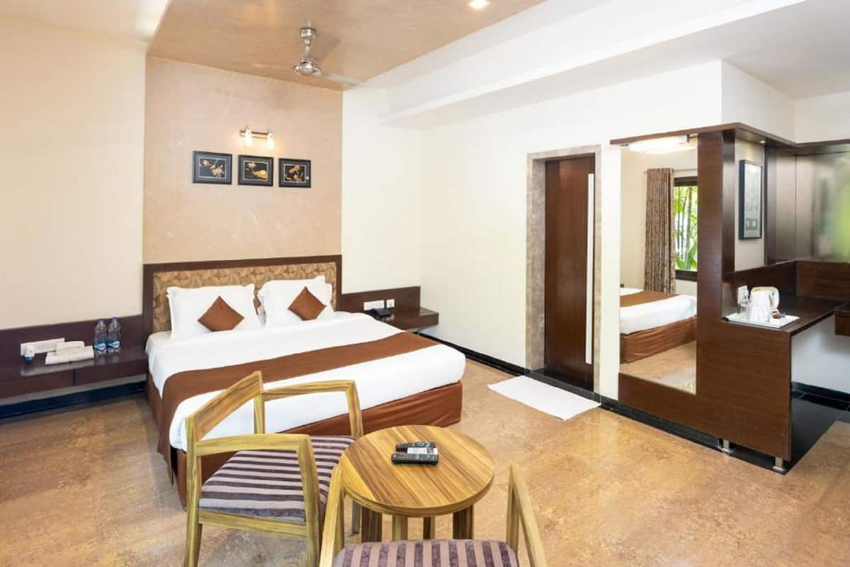 A hotel room with a large bed, a desk, a chair, and a small table.
