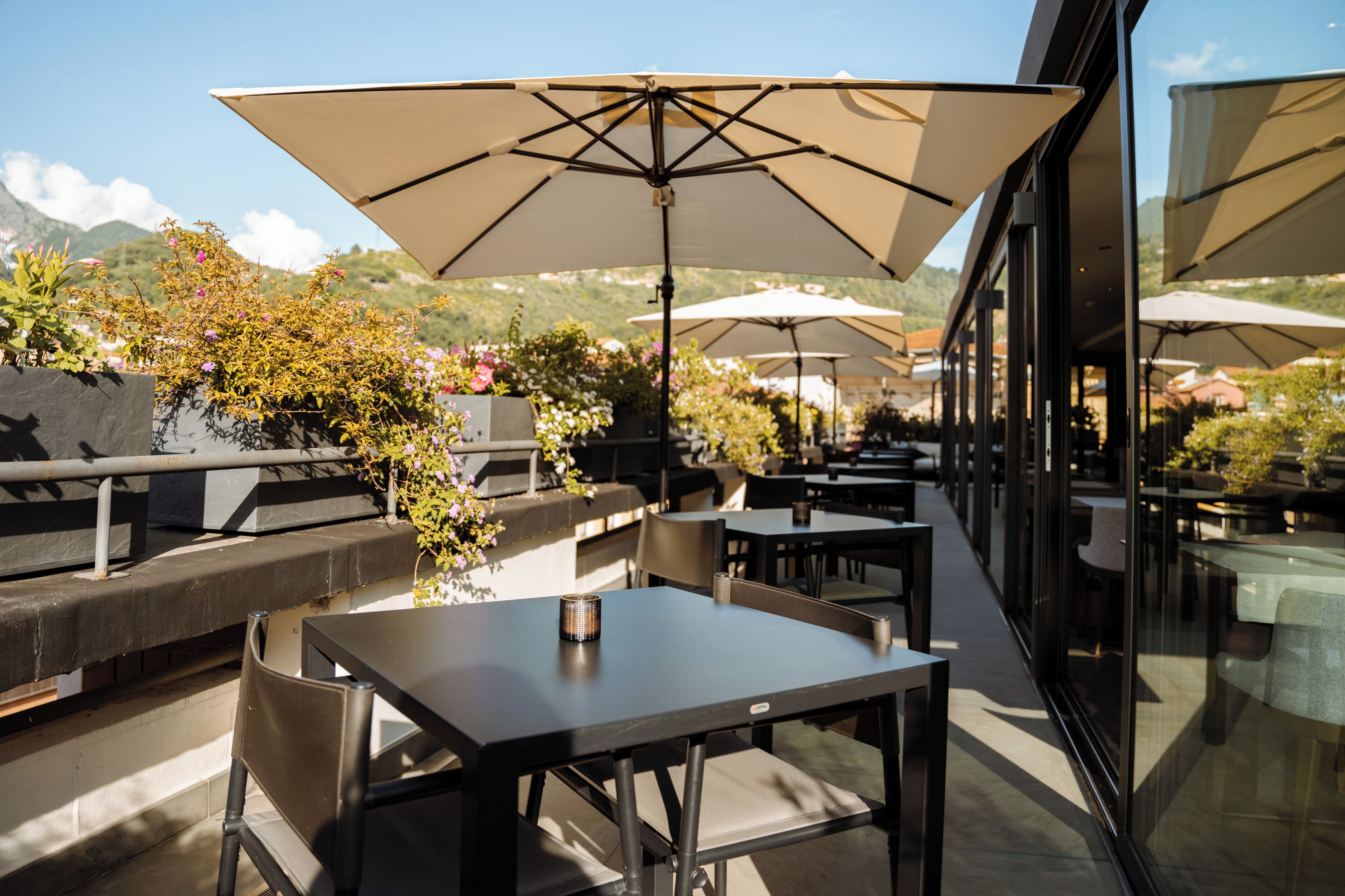 An outdoor seating area with tables and chairs, large umbrellas, and a view of the surrounding landscape.