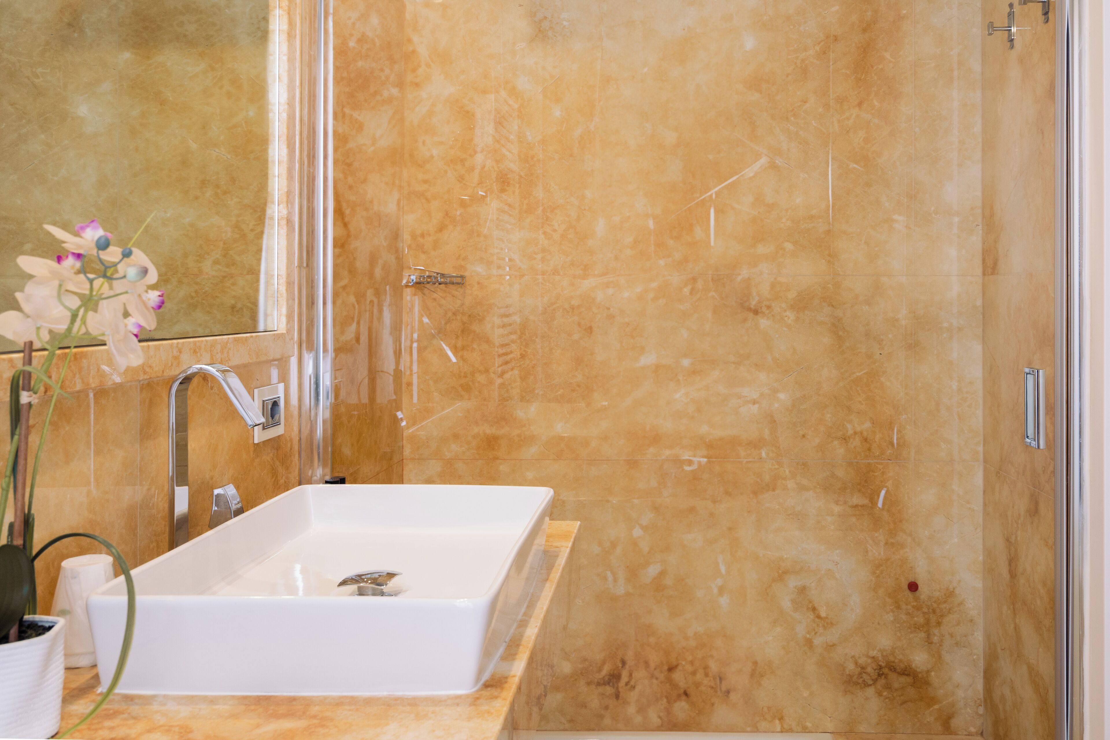 Une salle de bain avec un lavabo blanc, un miroir et un espace douche.