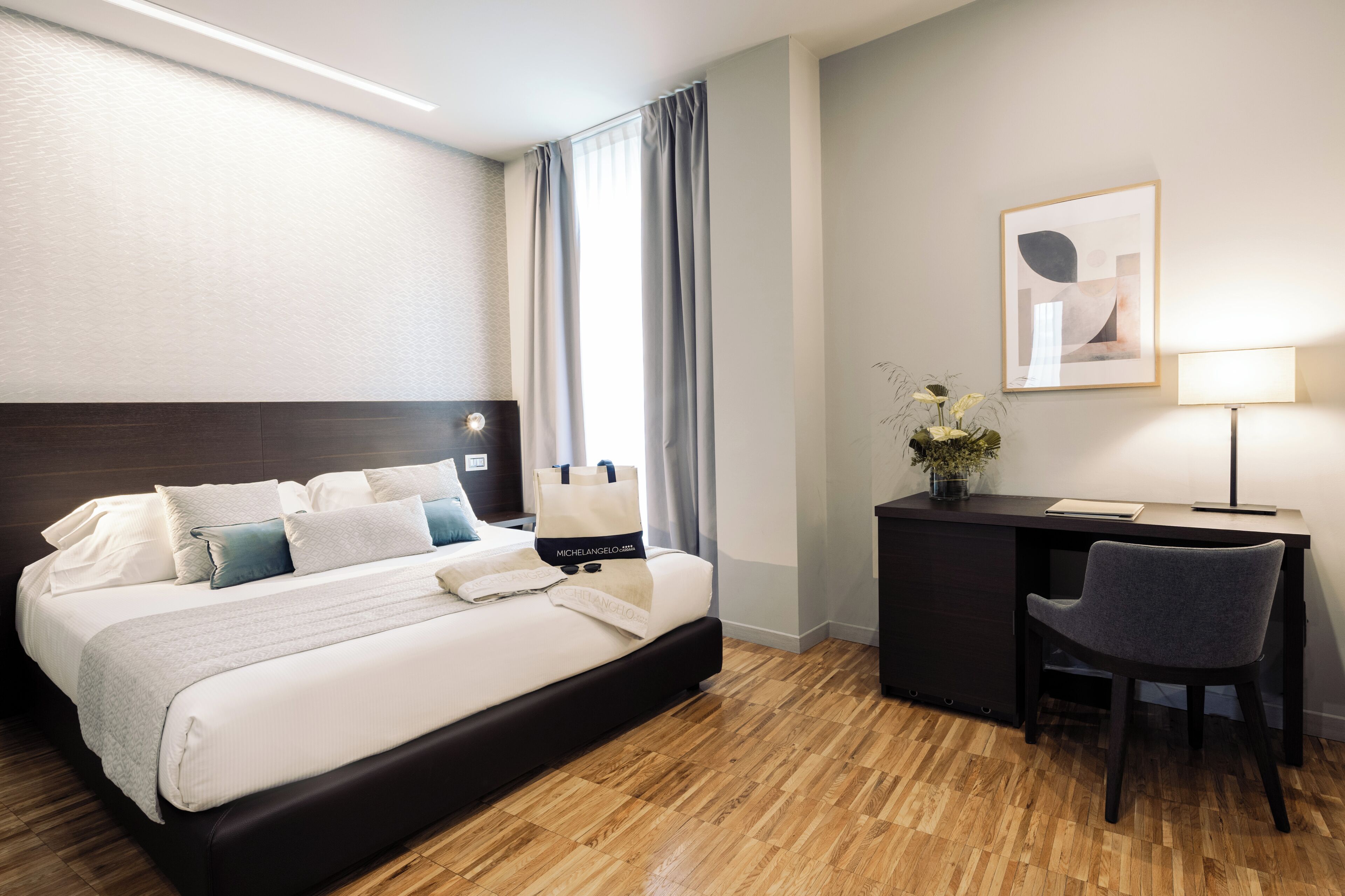 A hotel room with a bed, a desk, and a chair.