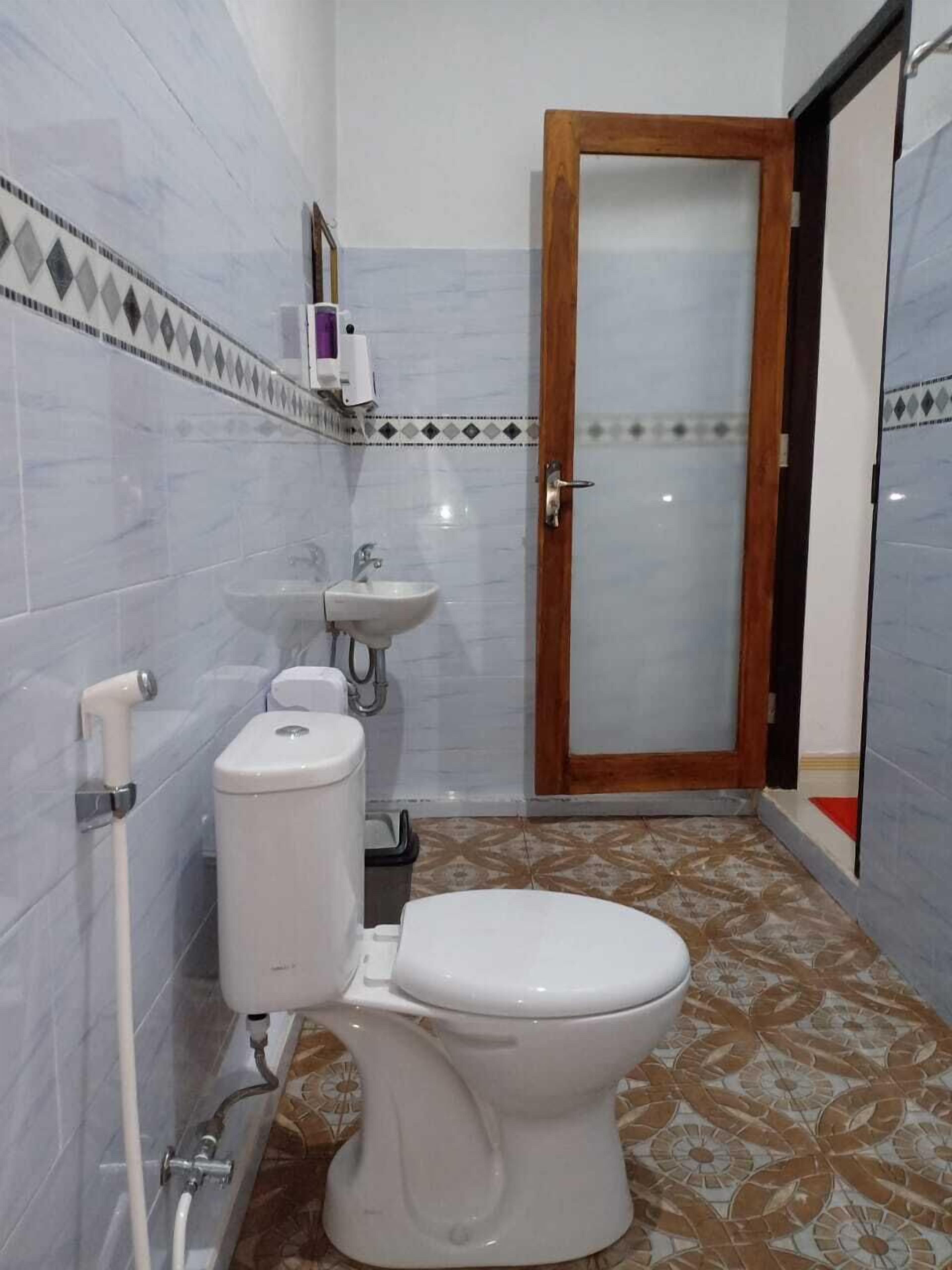 Pieni kylpyhuone, jossa on wc, pesuallas ja suihku.
