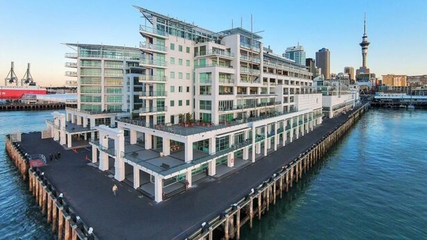 A waterfront hotel with multiple floors, a dock, and a view of the city skyline including a tower. - BEST Place Auckland Viaduct (Auckland)