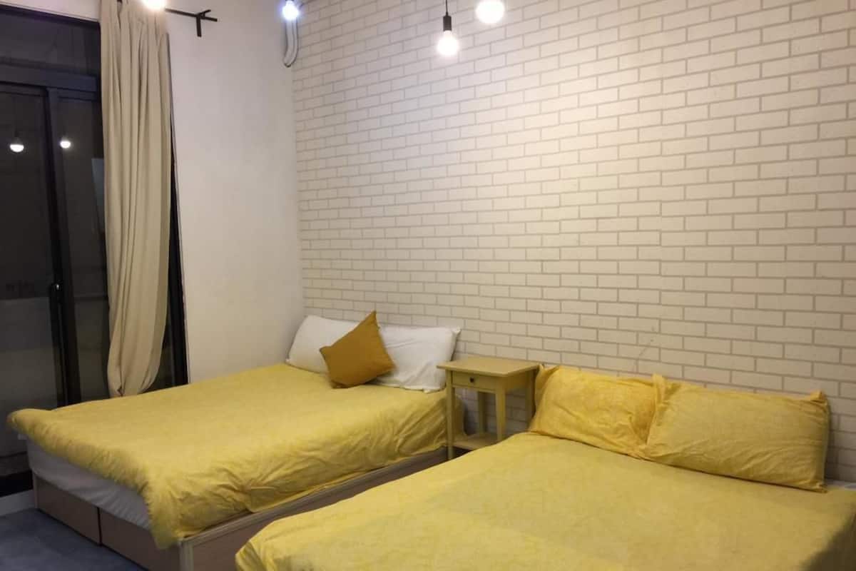 A room with two beds, each with yellow bedding and a wooden nightstand.