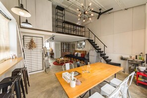 A spacious loft-style living area with a high ceiling, exposed beams, and a mezzanine level. - Memory Traveler (Tainan)
