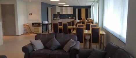 A spacious living area with a sofa, a coffee table, and a dining area with chairs and a table.