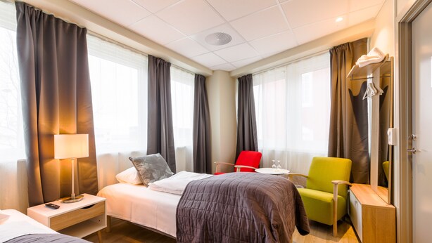 Una habitación de hotel con dos camas, un escritorio, una silla y un armario.