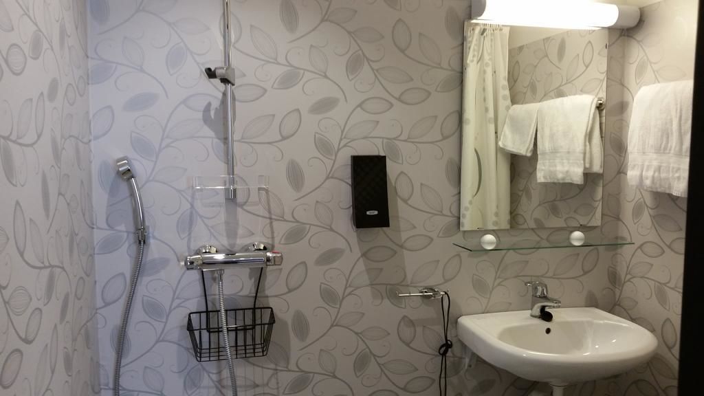 A bathroom with a shower, a sink, and a mirror with a towel rack.