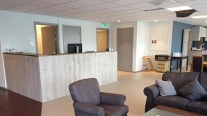 Un vestíbulo con mostrador de recepción, dos sillones, un sofá y una mesa de centro.