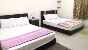 A hotel room with two beds, a nightstand with a lamp, and a small table with a plant.