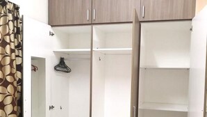 A walk-in closet with open doors, featuring a mirrored closet door, multiple shelves, and drawers.