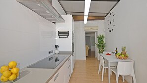Une cuisine moderne avec des meubles blancs, une cuisinière encastrée et un coin repas comprenant une table et des chaises.