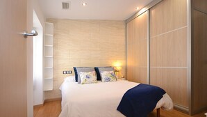 Une chambre à coucher avec un lit, un plancher en bois, une armoire et une table de chevet avec une lampe.