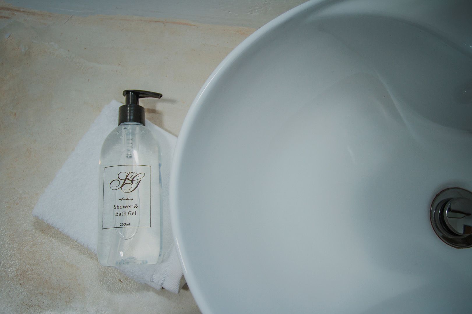 Een wastafel met een fles douche- en badgel ernaast.