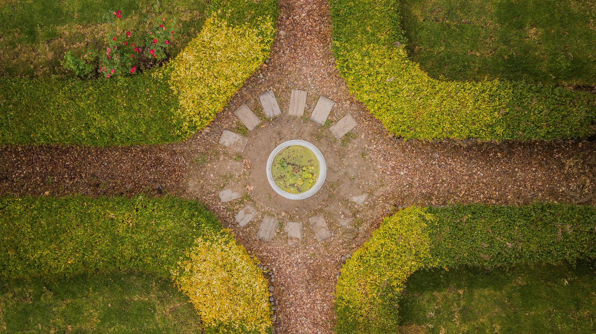 A circular intersection with a central circular area, surrounded by a gravel path and bordered by trimmed hedges.