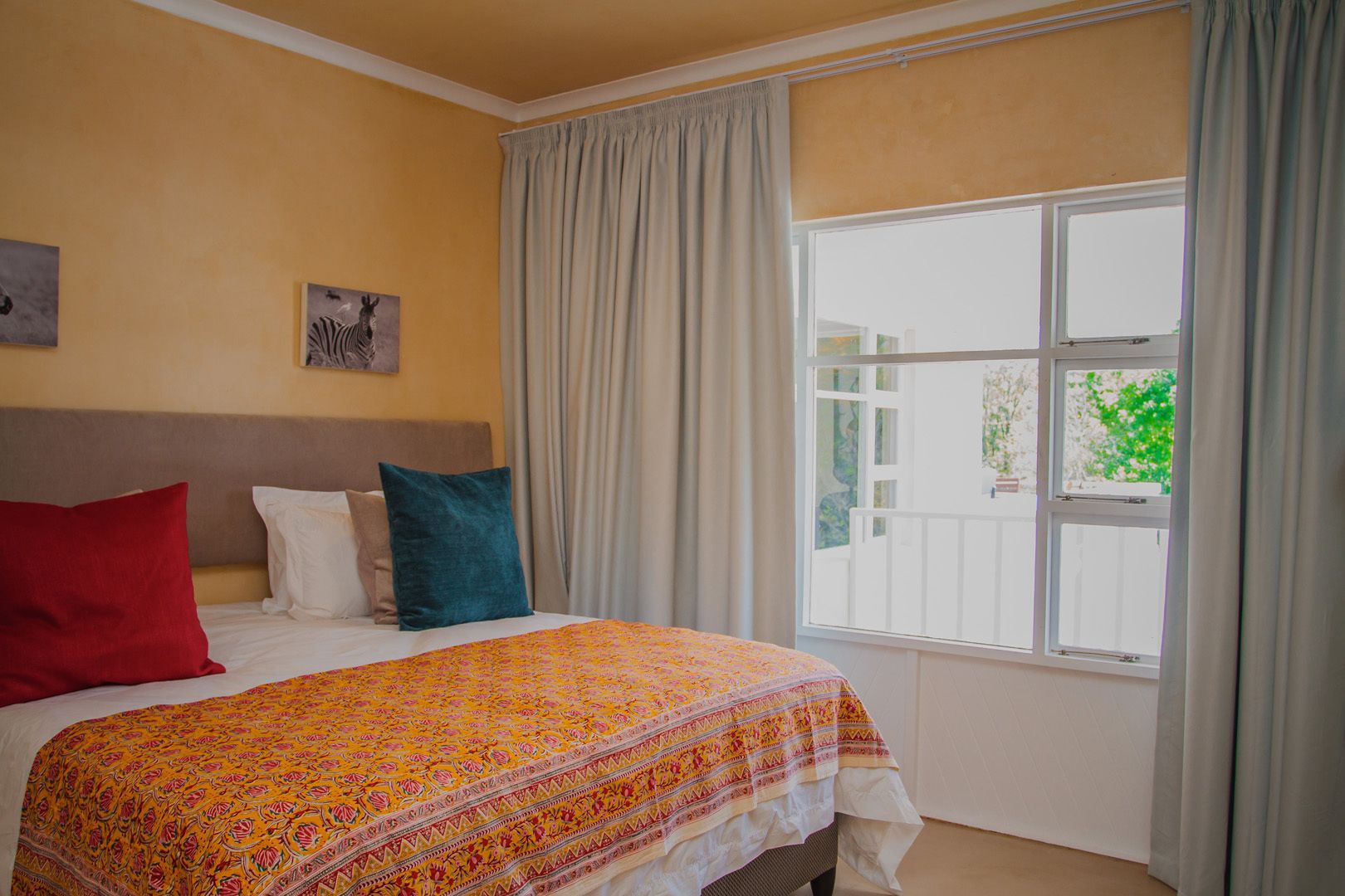 A bedroom with a bed, a headboard, and a window with curtains.